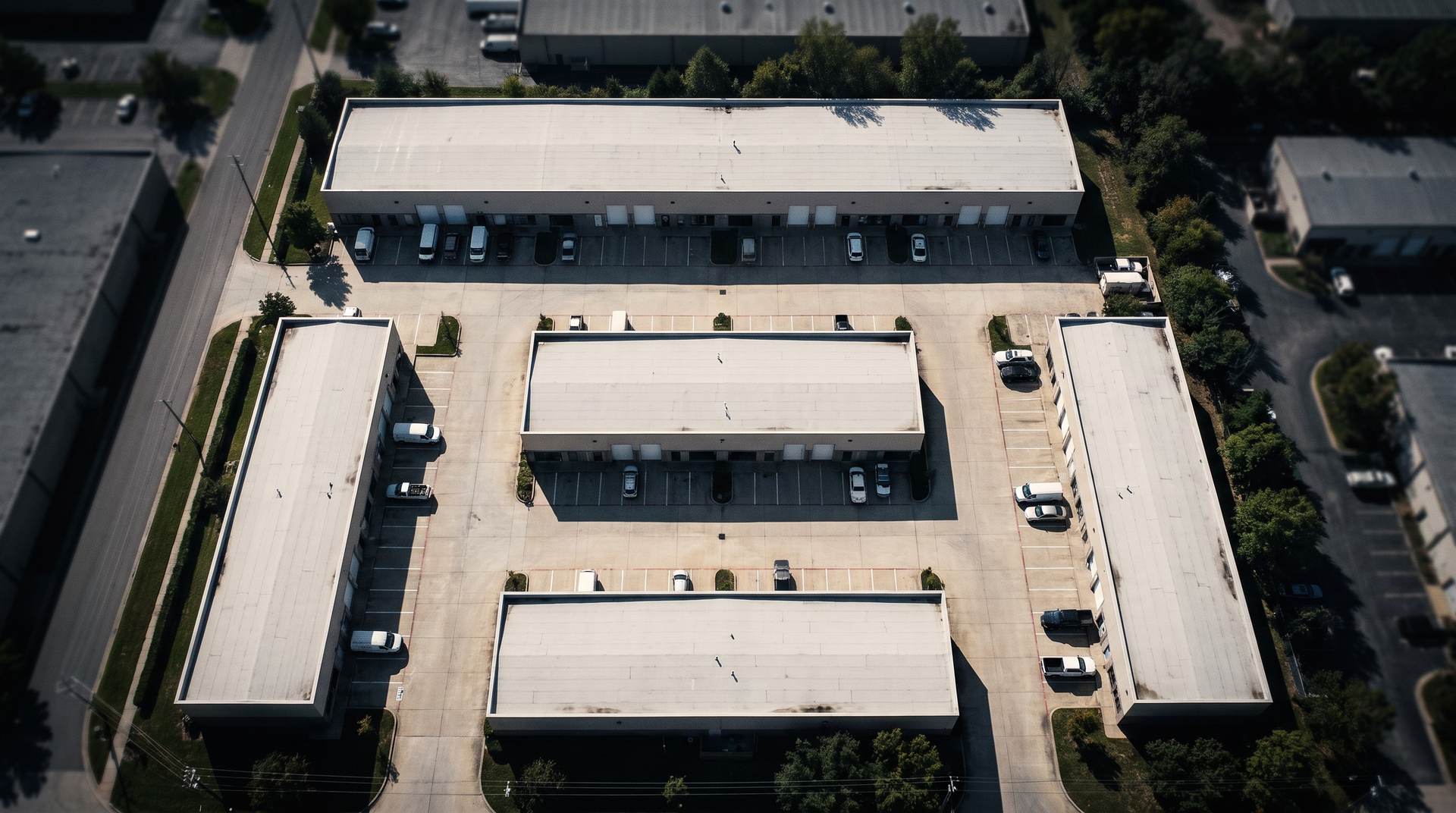Aerial view of a small-bay industrial park: several long light-industrial buildings arranged around shared concrete drive aisles